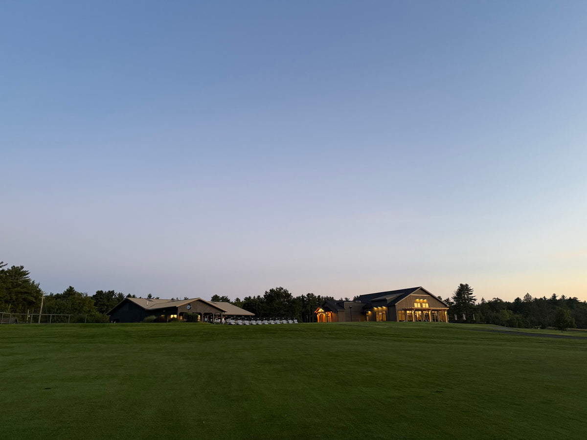 The clubhouse at dusk across the fairway, lights on inside, at the Bryan Martin Foundation scramble